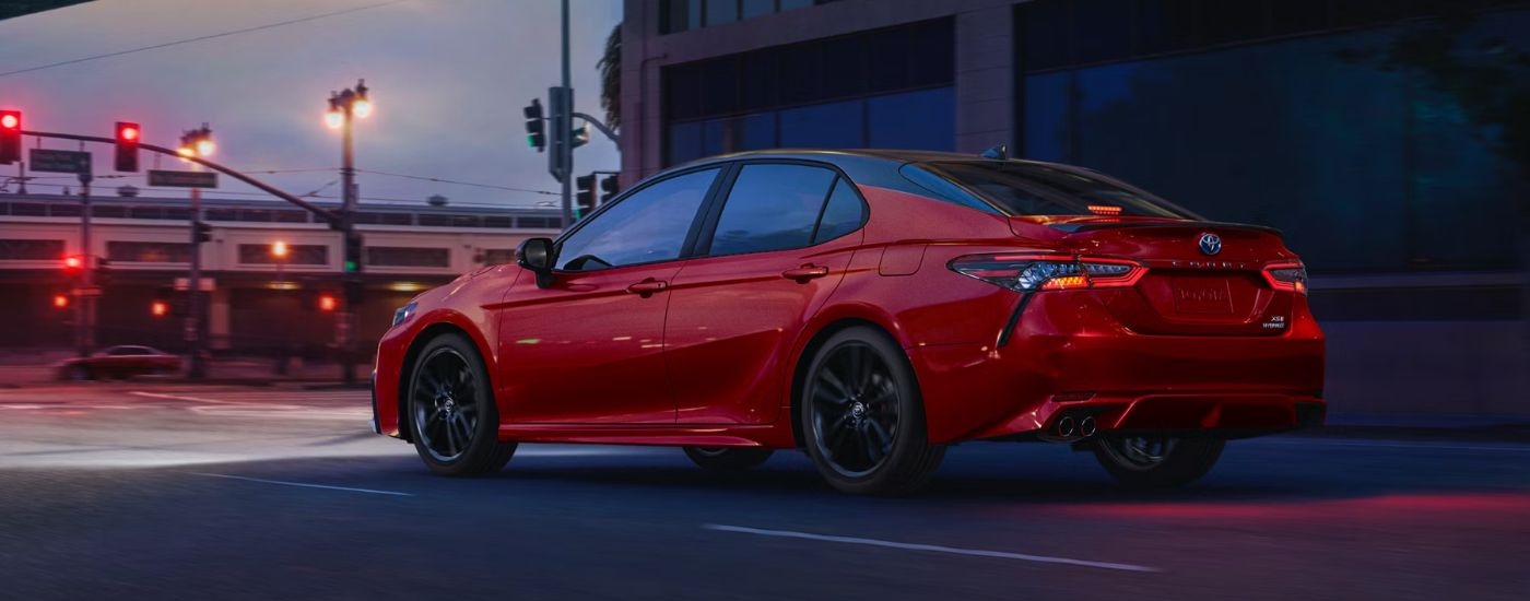 A red 2024 Toyota Camry for sale is shown from the rear at an angle.