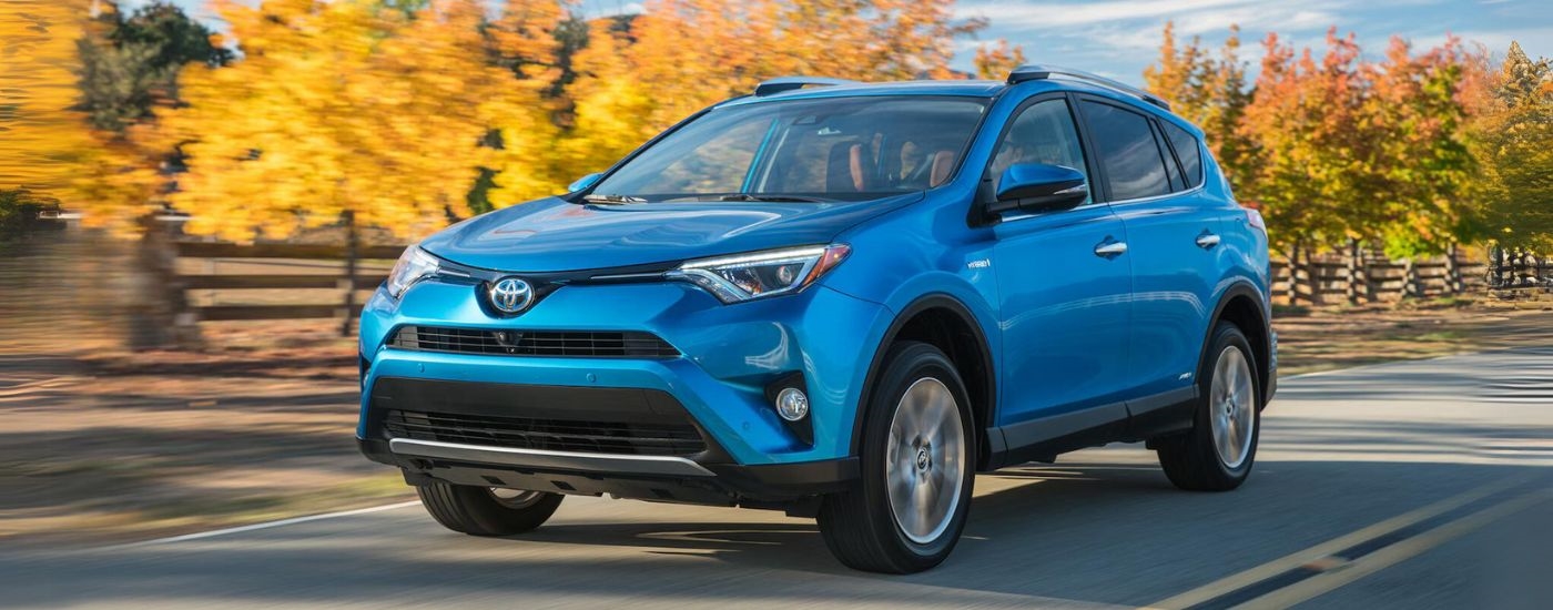 A blue 2016 Toyota RAV4 driving down a road.