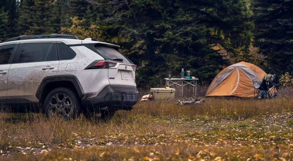 A white 2023 Toyota RAV4 TRD is shown at a campsite.