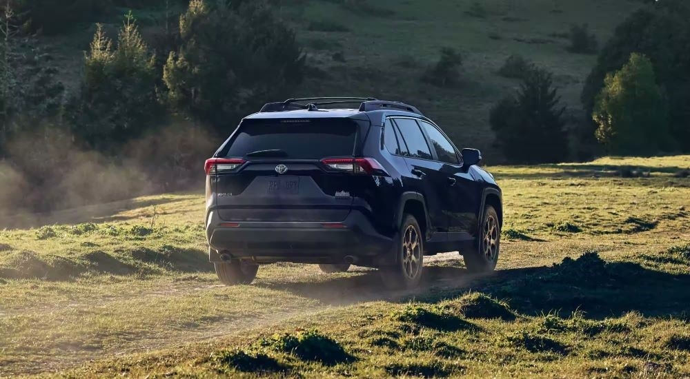 A dark blue 2023 Toyota RAV4 Hybrid Woodland Edition is shown on a path after leaving a Toyota dealer.