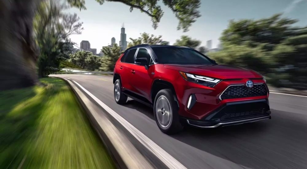 A red 2023 Toyota RAV4 Prime is shown driving to a Toyota dealer near White Plains, NY.