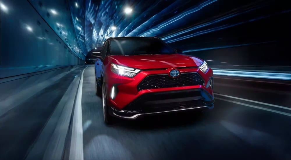 A red 2023 Toyota RAV4 Prime is shown driving in a tunnel.