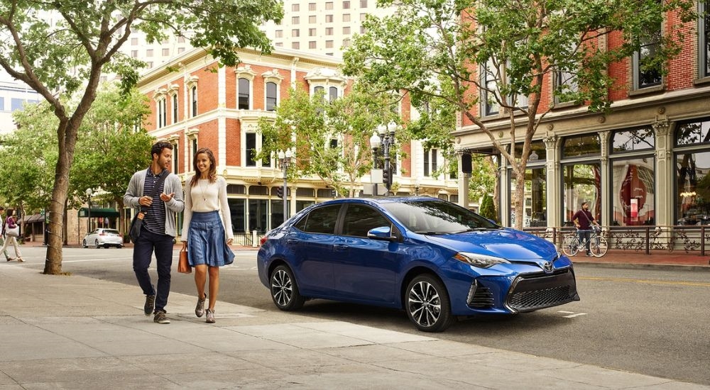 A blue 2019 Toyota Corolla is shown parked near a store.