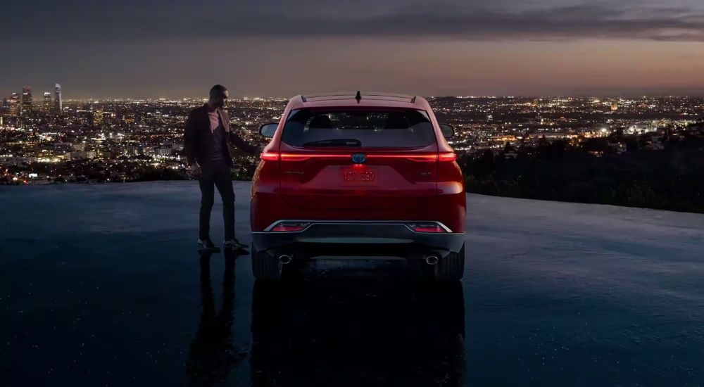 A red 2023 Toyota Venza Nightshade Edition is shown overlooking a city skyline at night.