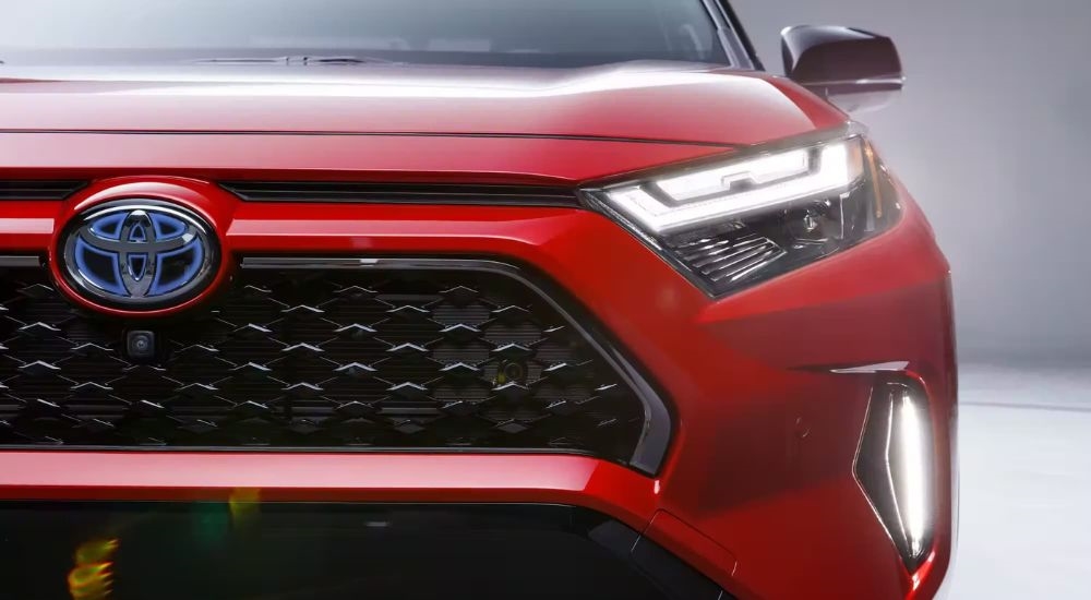 A close-up shows the grille on a red 2024 Toyota RAV4 Prime.