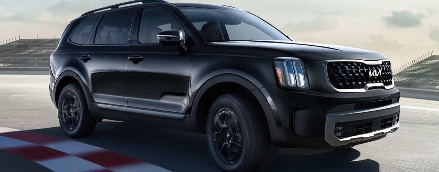 A black 2024 Kia Telluride driving over a finish line.