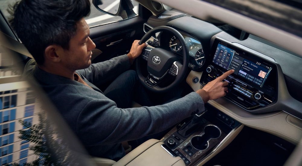 A man using the infotainment screen in a 2024 Toyota Highlander Platinum for sale.