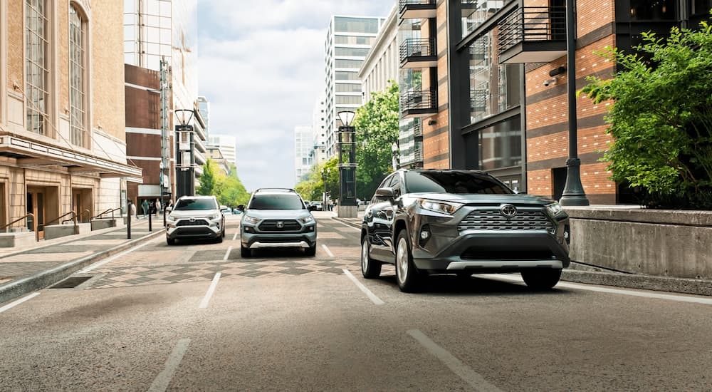 Three 2021 Toyota RAV4s are driving down a city street.