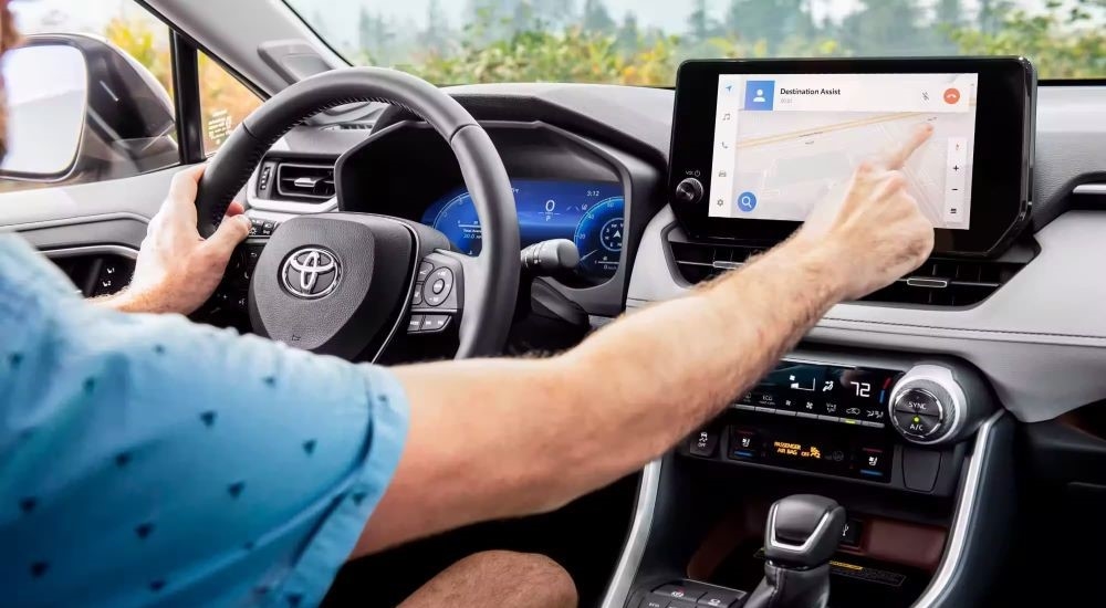 A man is using the infotainment screen in a used 2023 Toyota RAV4 for sale.