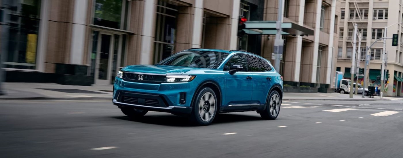 A teal 2024 Honda Prologue Elite is shown driving to a Honda dealer near Washingtonville.