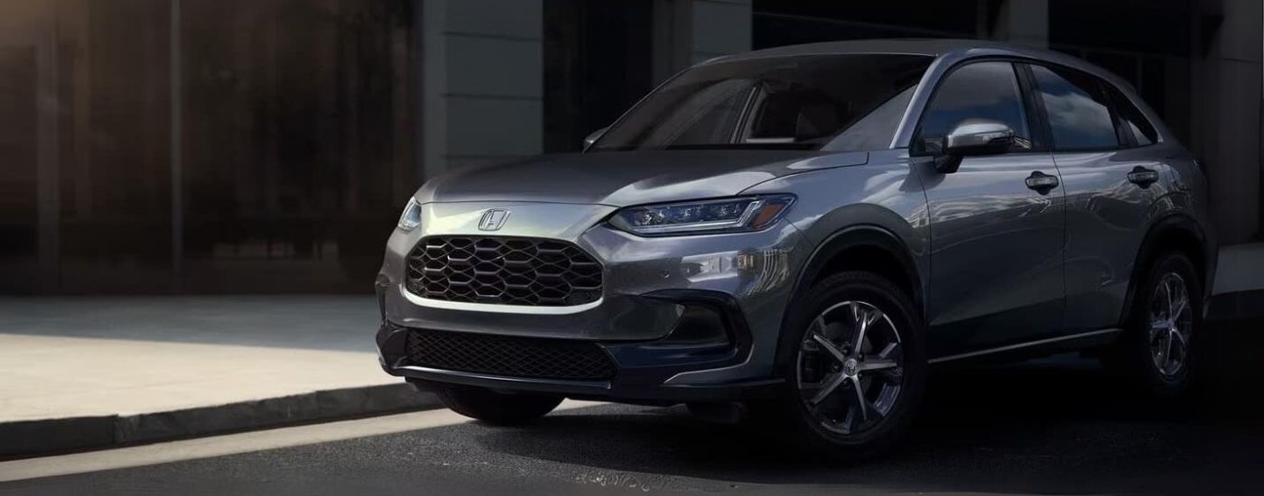 A grey 2025 Honda HR-V EX-L is shown parked in front of a building.