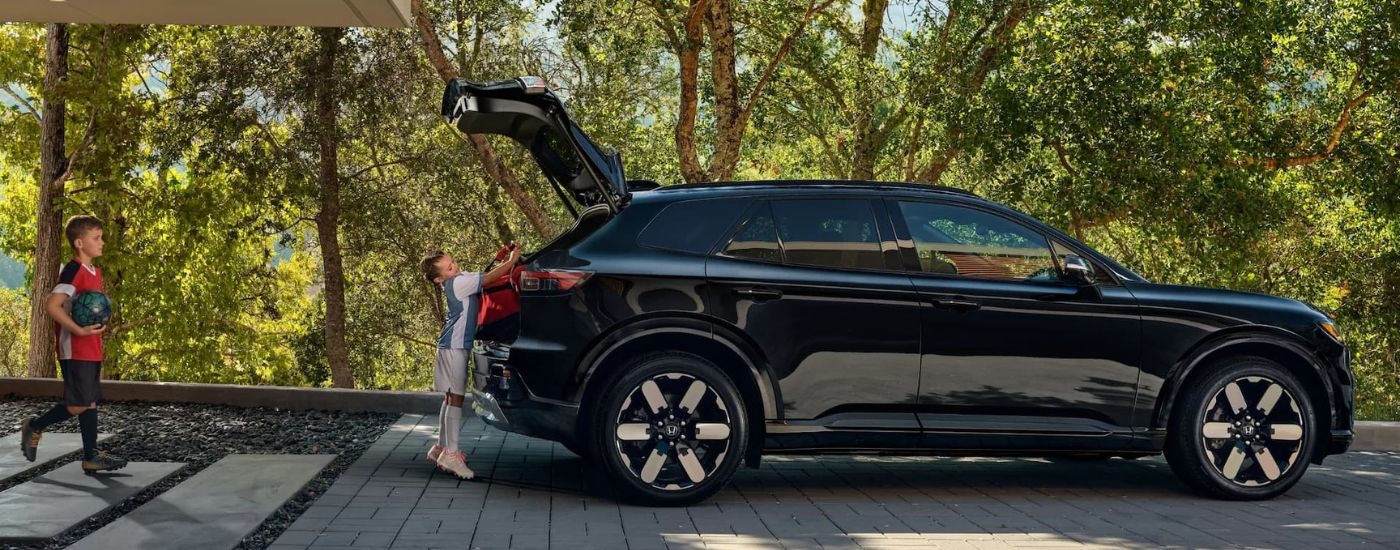 A child is shown putting a red bag in a black 2024 Honda Prologue Elite.