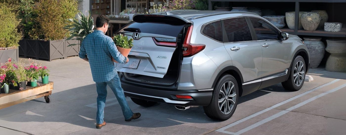 A person is shown holding plants near a silver 2021 Honda CR-V Touring after looking at SUVs for sale.