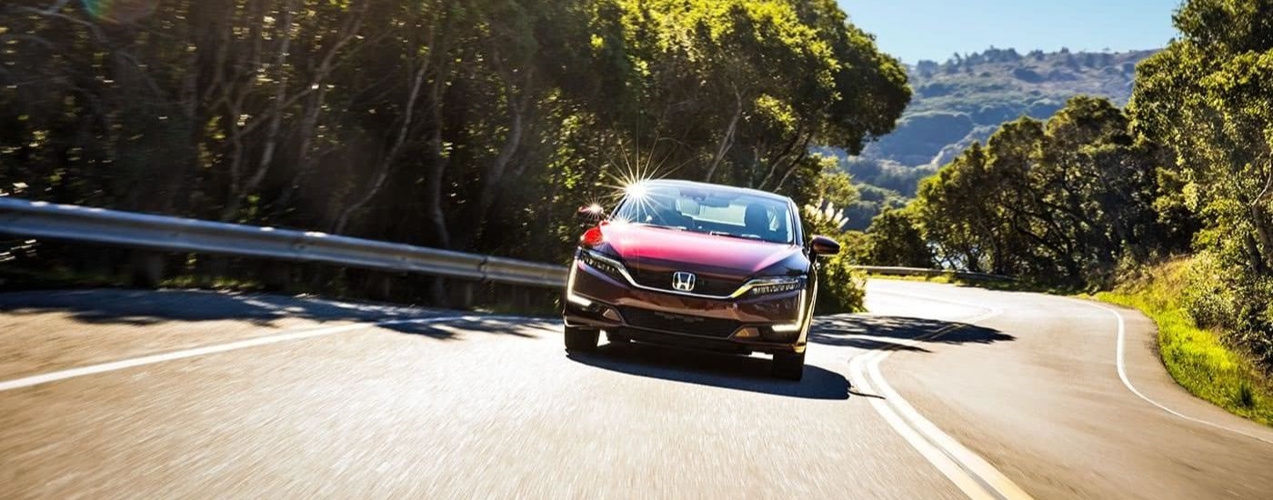 A red 2017 Honda Clarity Fuel Cell EX is shown driving to look at cars for sales.