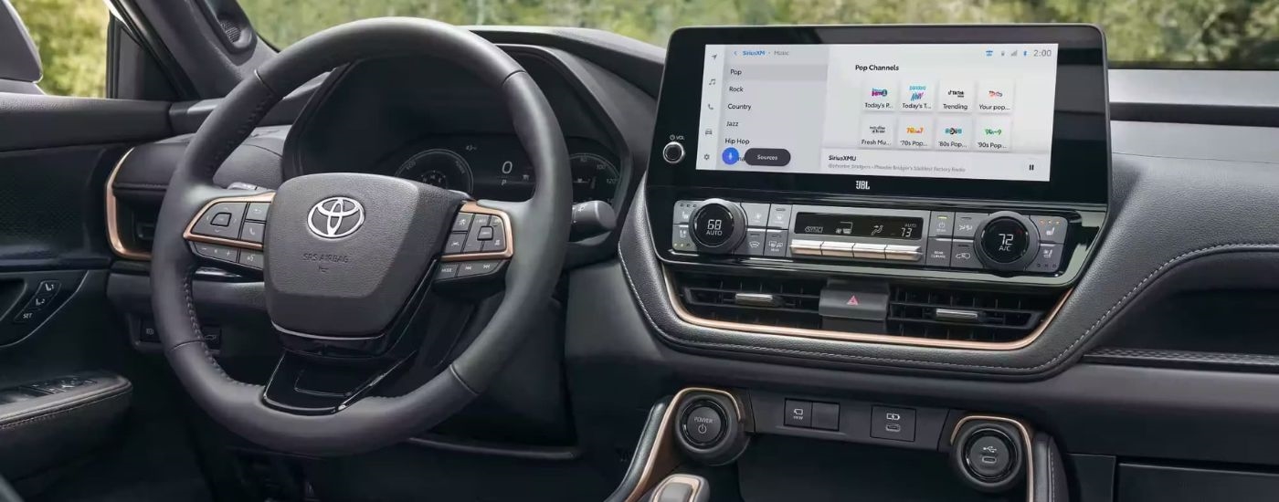 The black interior and infotainment screen are shown in a 2024 Toyota Grand Highlander.