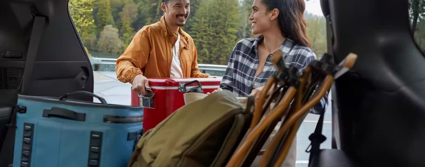 A person is shown loading a red cooler in a 2024 Toyota Grand Highlander.