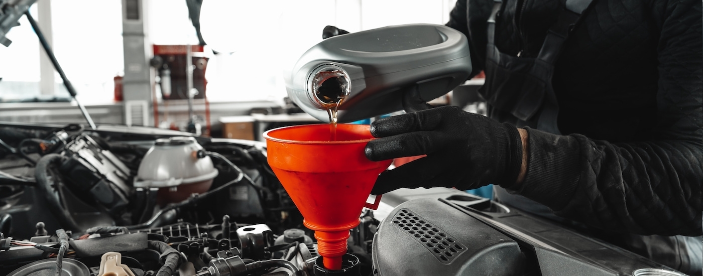 A technician adding engine oil during an oil change service.