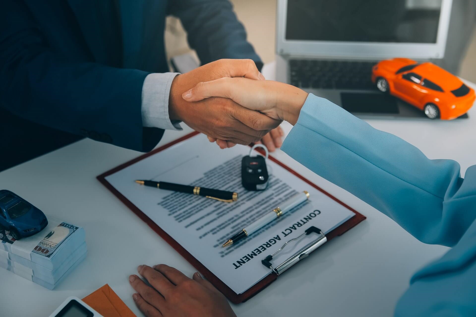 Used car deal with POV of customer shaking hands with sales advisor, featuring keys and signed form