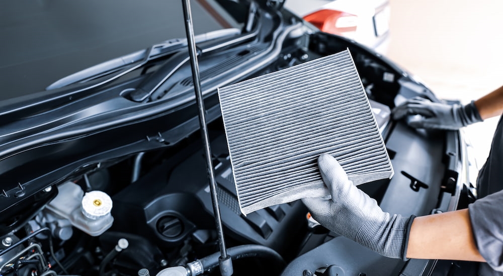 A technician inspecting a car's engine air filter.