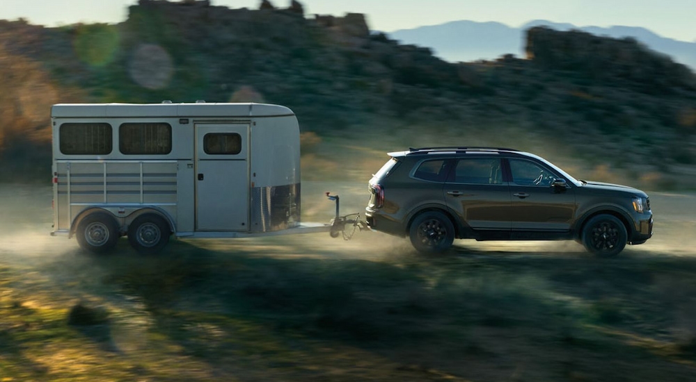 A grey 2024 Kia Telluride X-Pro towing a trailer.