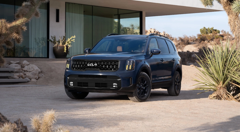 A black 2024 Kia Telluride X-Pro parked in a desert driveway.