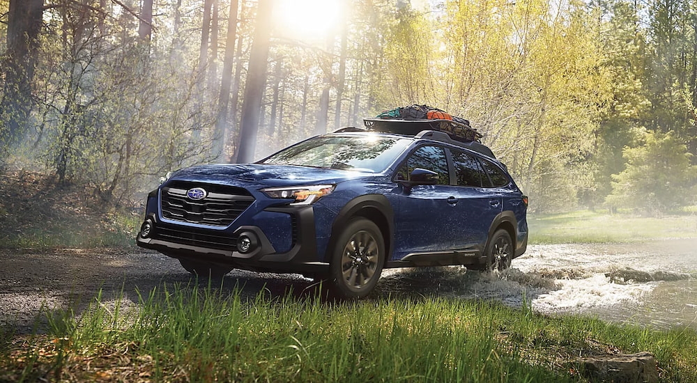 A blue 2024 Subaru Outback Onyx Edition XT off-roading in the woods.