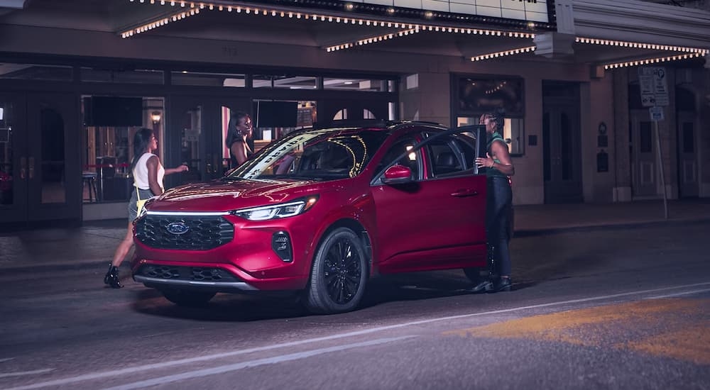 Friends getting into a red 2025 Ford Escape parked under a marquee.