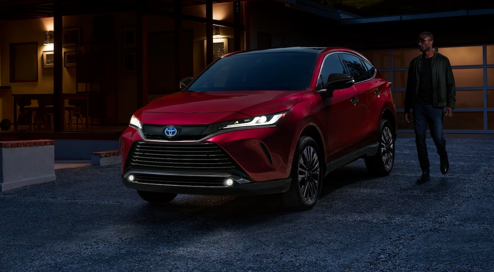 A man walking to a red 2024 Toyota Venza Nightshade Edition parked in the dusk.