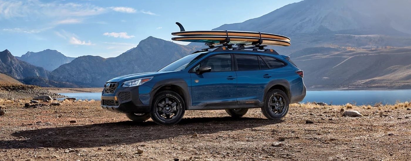 A blue 2024 Subaru Outback Wilderness parked off-road and angled left.