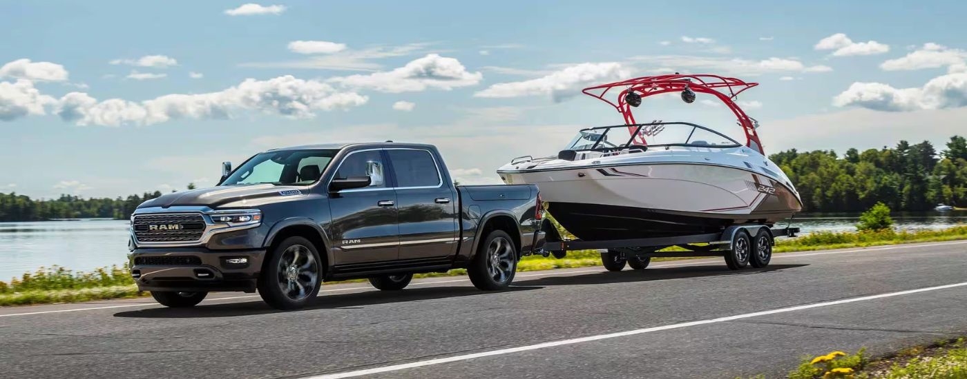 A grey 2024 Ram 1500 is shown towing a boat after visiting a Ram dealership.