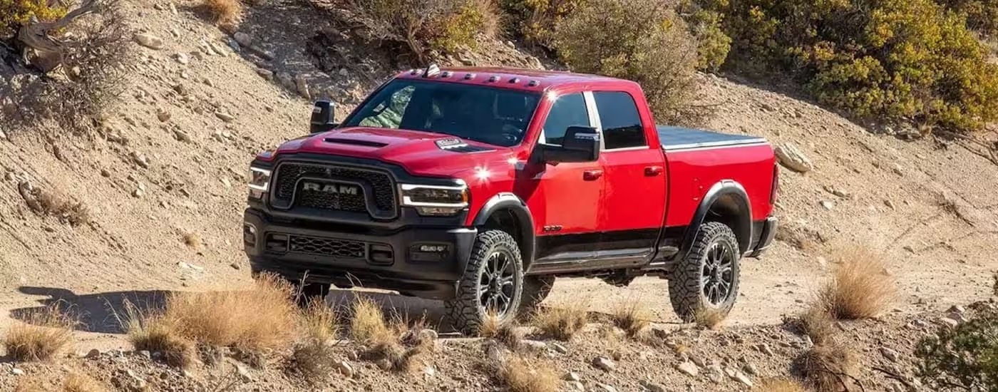 A red 2024 Ram 2500 for sale is shown from the front at an angle while off-road.
