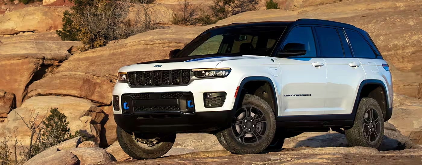 A white 2024 Jeep Grand Cherokee Trailhawk 4xe parked on boulders.