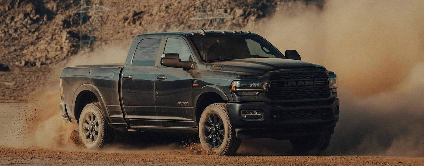 A black 2023 Ram 2500 HD Cummins is shown from the front at an angle while off-road after leaving a Ram dealer near Red Hook.