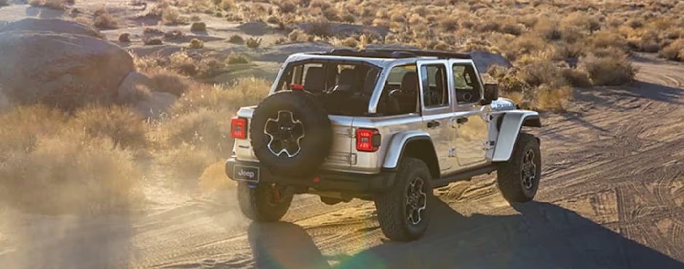 A silver 2024 Jeep Wrangler 4xe is shown from the rear at an angle.