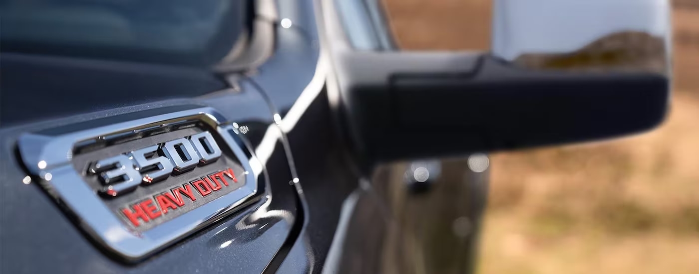 A close-up of a badge on the hood of a black 2024 Ram 3500 is shown.