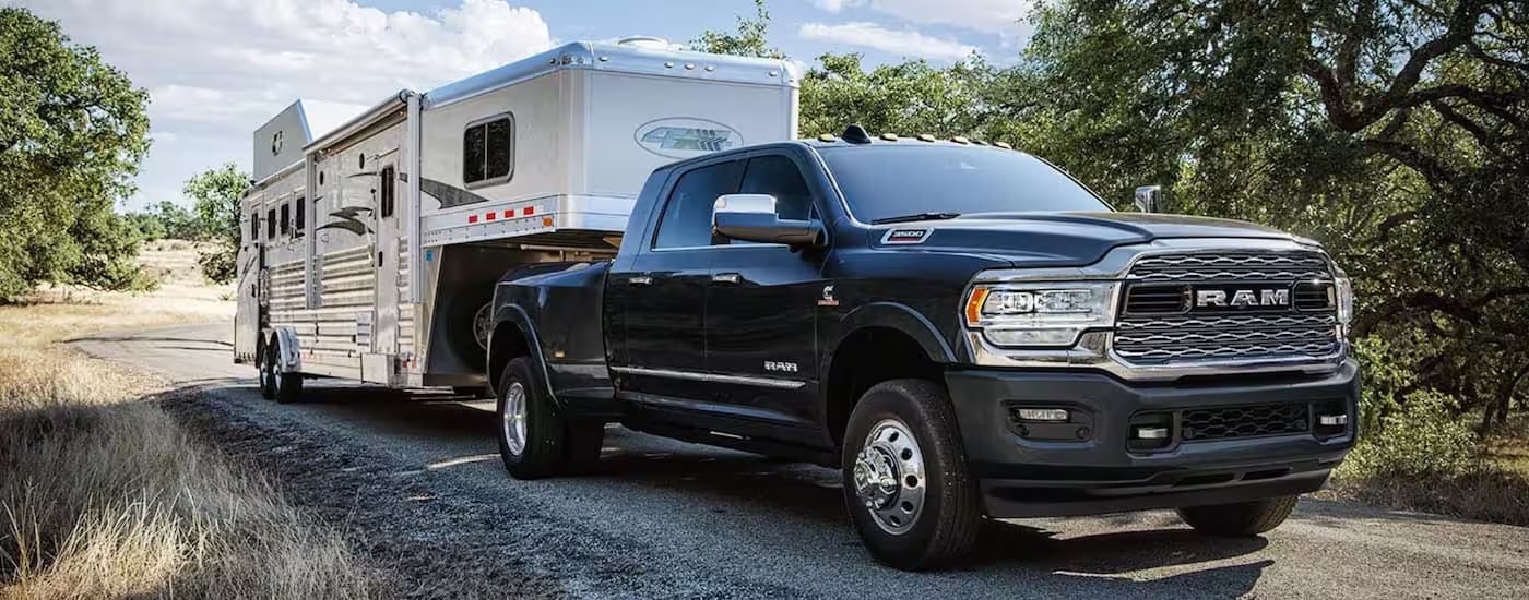 A black 2019 Ram 3500 is shown towing a large white trailer.