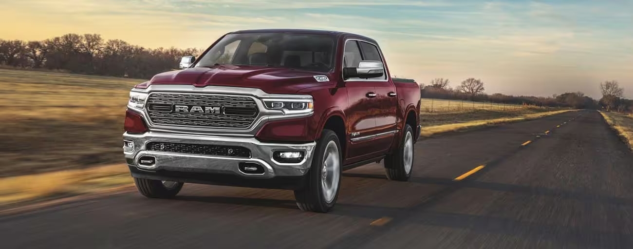 A red 2020 Ram 1500 is shown from the front driving on an open road after leaving a used Ram dealership.