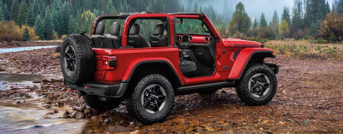 Rear view of a red 2019 Jeep Wrangler Rubicon parked off-road after visiting a used Jeep dealership.