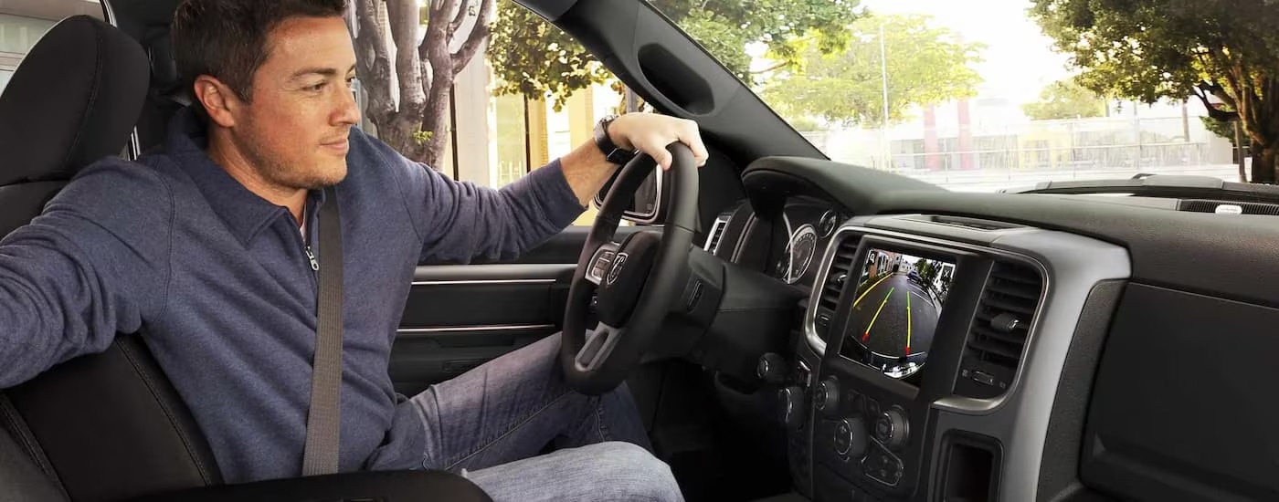 A man is shown using the back-up camera in a 2022 Ram 1500.