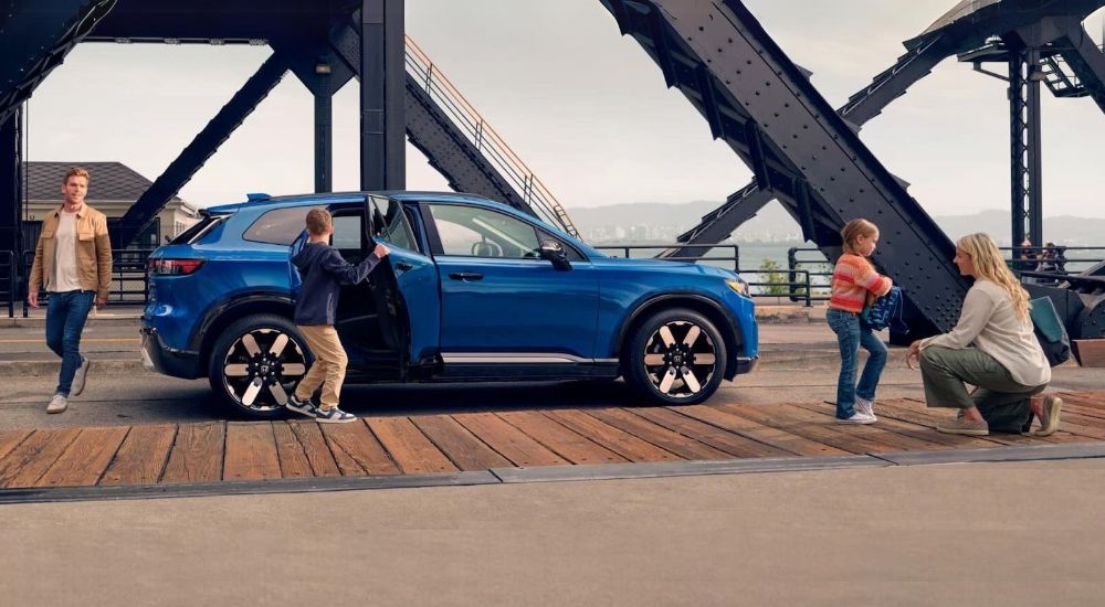 A family is shown near a blue 2024 Honda Prologue Elite.