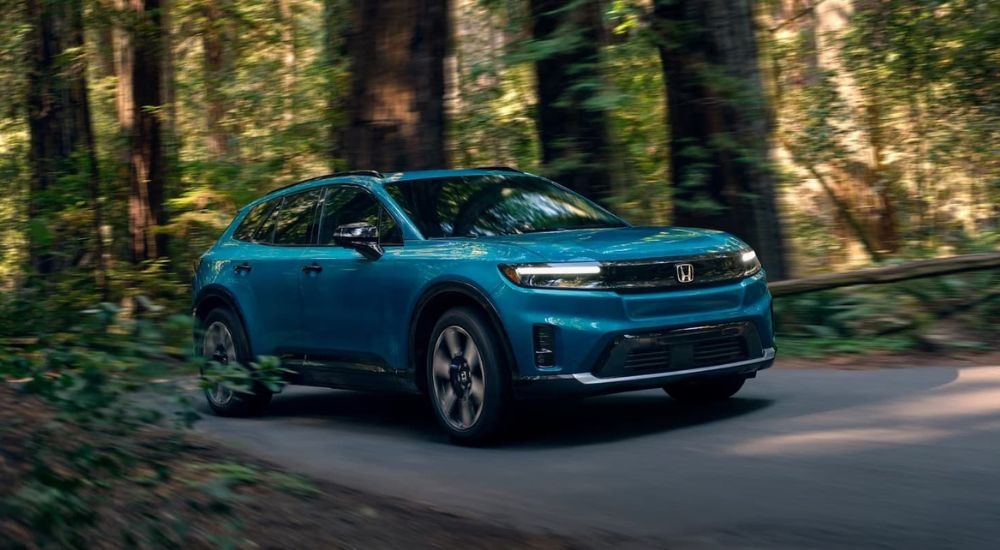 A teal 2024 Honda Prologue Elite is shown driving to a Honda dealer near Washingtonville.