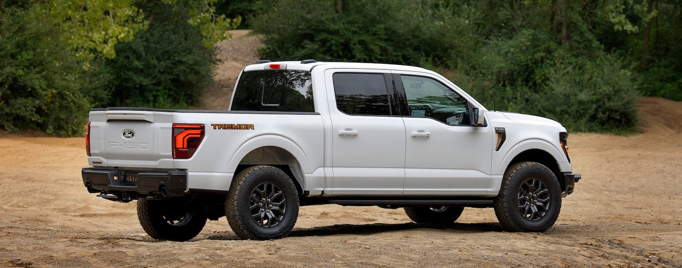 A white 2024 Ford F-150 Tremor is shown from the side while parked off-road.