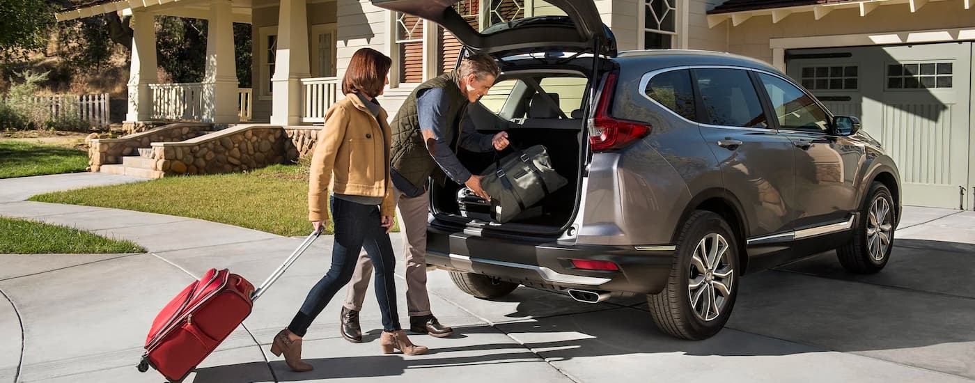 A man and woman loading luggage into the back of a silver 2022 Honda CR-V Touring.