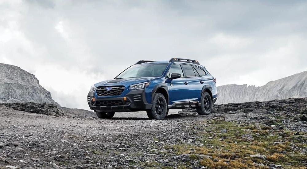 A blue 2023 Subaru Outback Wilderness parked off-road and angled left.