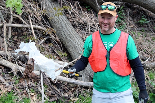 Man holding trash along Route 403 next to Greenhouse Park