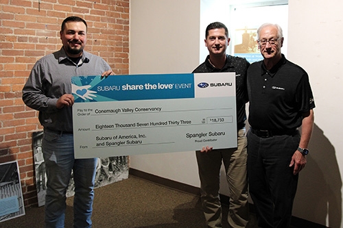 Men standing with Share the Love check at Heritage Discovery Center
