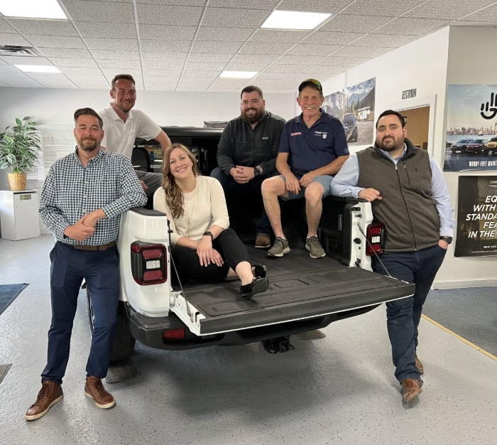 A group of people in a Jeep Gladiator's bed.
