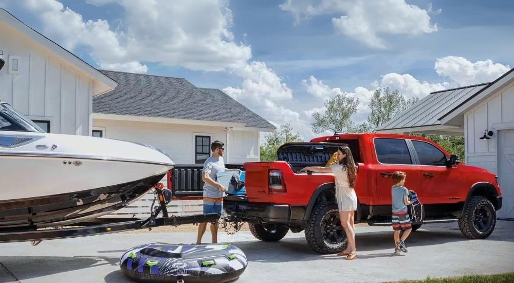 A family is shown near a red 2023 Ram 1500 parked on a driveway.