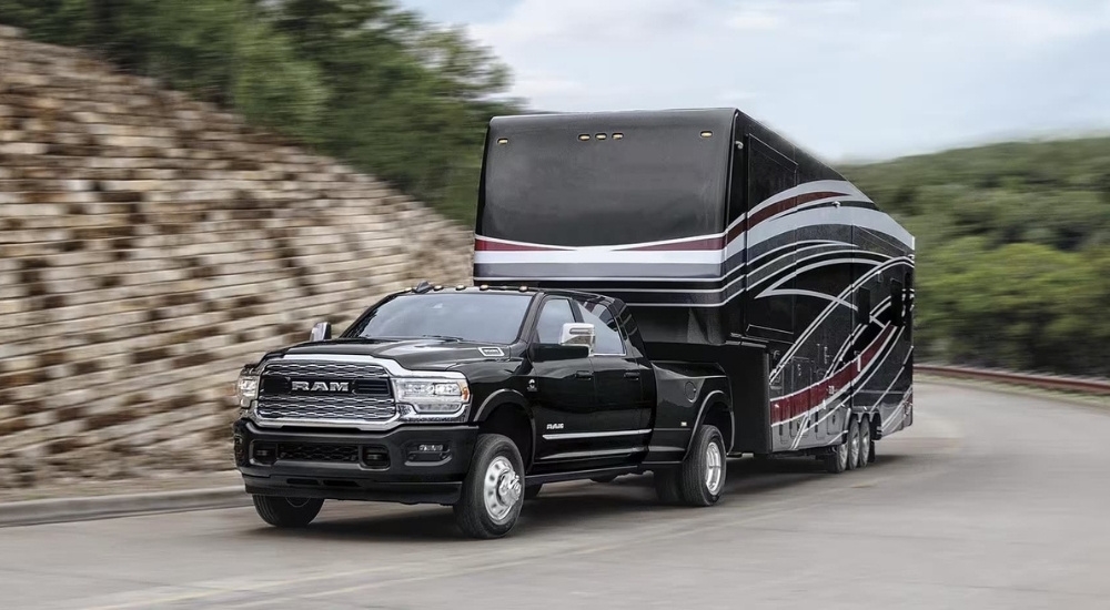 A black 2023 Ram 3500 is shown towing a trailer after leaving a Ram dealer near Kingston.