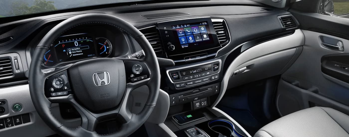 The steering wheel and digital displays in the cabin of a used 2022 Honda Pilot Elite for sale near Mill Creek.